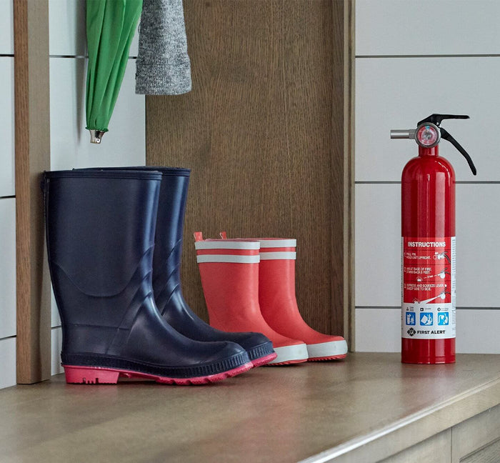 A fire extinguisher is next to some rain boots.